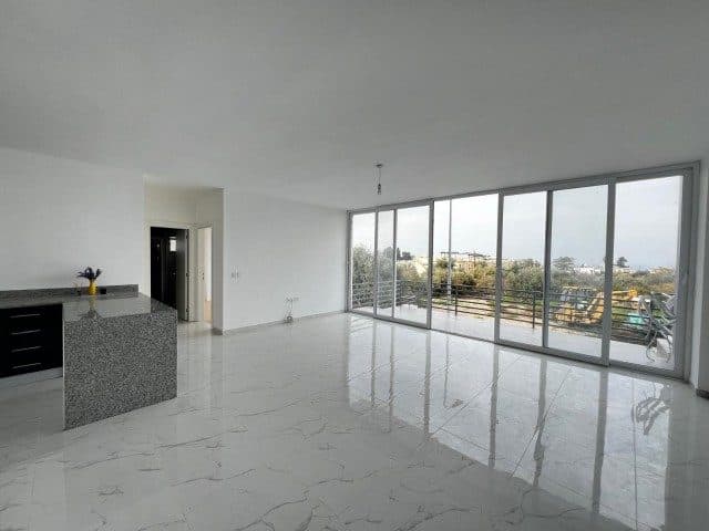 Boş salon, granit tezgâhlı mutfak ve geniş camlı balkon