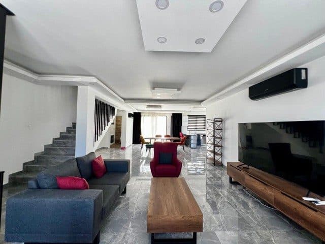 Gray corner sofa, red armchair, and large-screen television