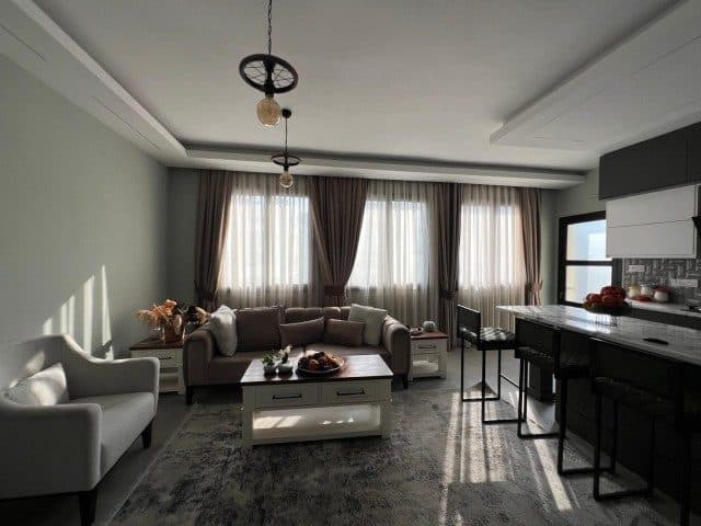 Gri koltuklar, orta sehpa ve mutfak barı aynı alanda