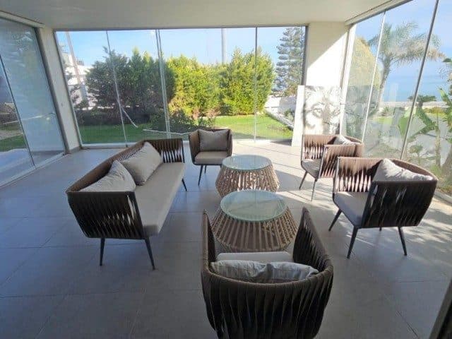 Wicker-style chairs and round tables in a glass-enclosed seating area