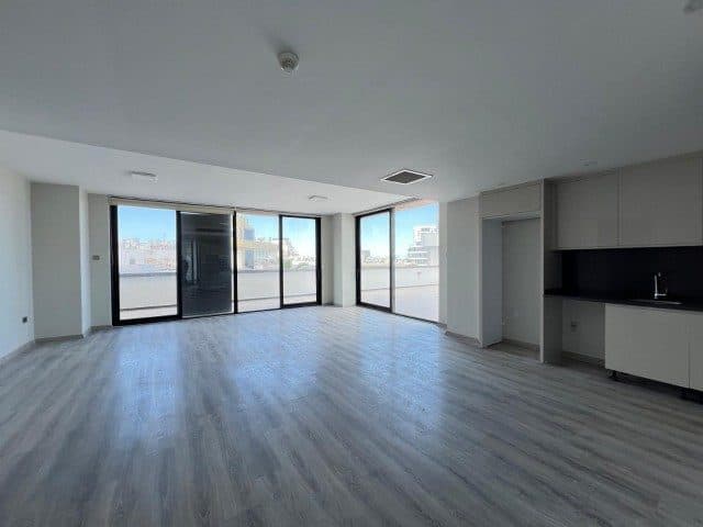 Boş salon, gri zemin ve sürgülü cam kapılarla terasa açılıyor.