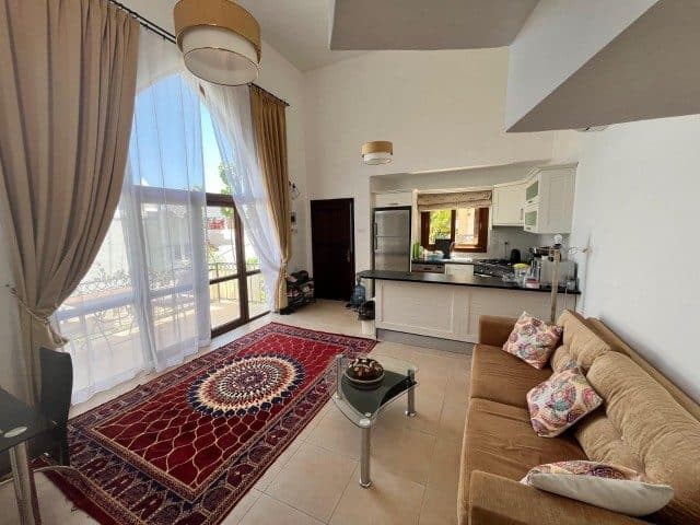 Bej kanepe ve desenli halı, geniş balkon kapısının yanında