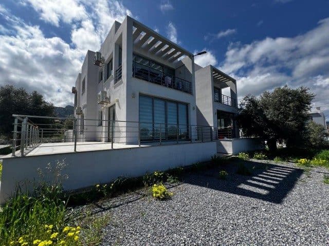 Açık renkli cephe, koyu korkuluklar ve üstü pergolalı balkon