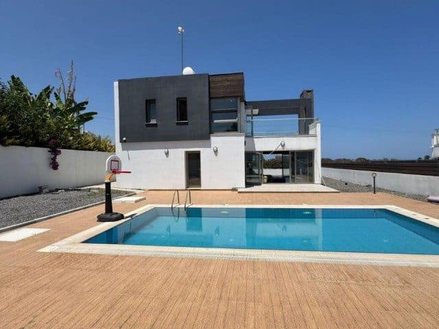 A pool in front of a villa with a modern facade