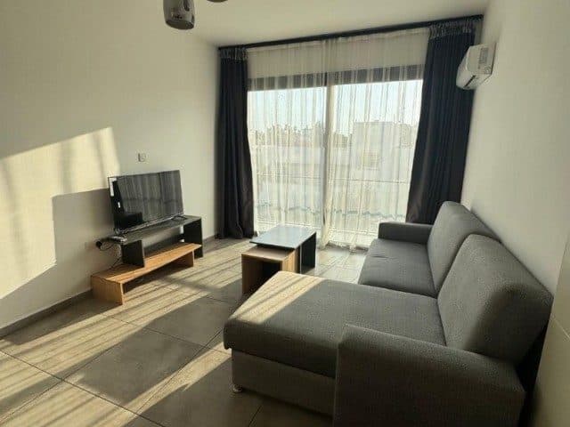 Gri köşe koltuk, TV ünitesi ve geniş camlı balkon kapısı