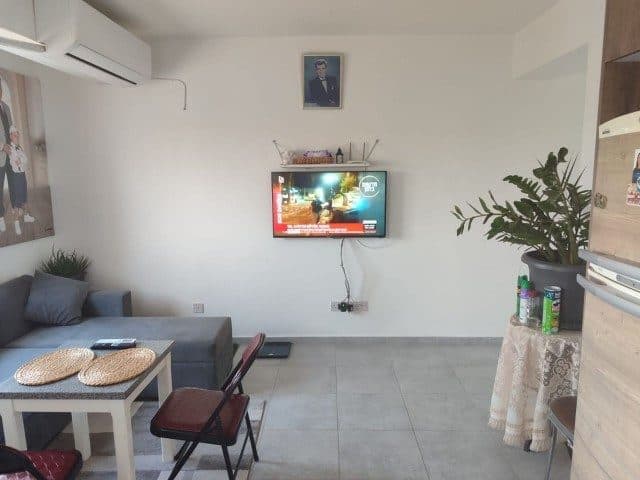 Gri köşe koltuk, duvara asılı televizyon ve üstte klima