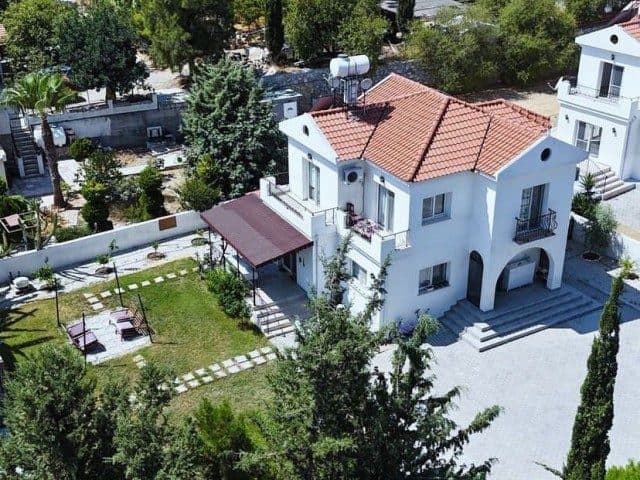 Yukarıdan çekimde kiremit çatılı ev, bahçe ve araç alanı görülüyor.