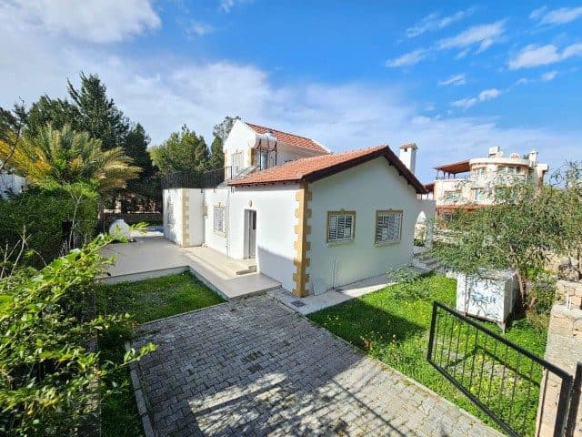 Kırmızı kiremit çatılı ev, taş döşeli giriş ve çim alanla çevrili.