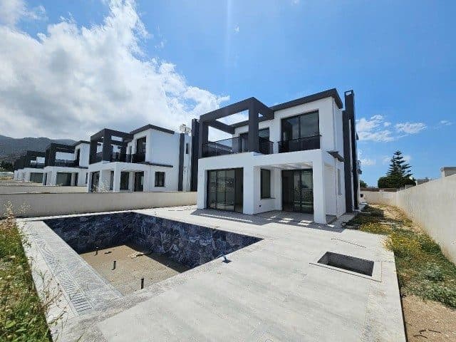 Beyaz cepheli villanın önünde boş havuz ve geniş taş döşeme