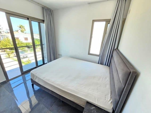 Çift kişilik yatak, gri başlık ve balkon kapısı