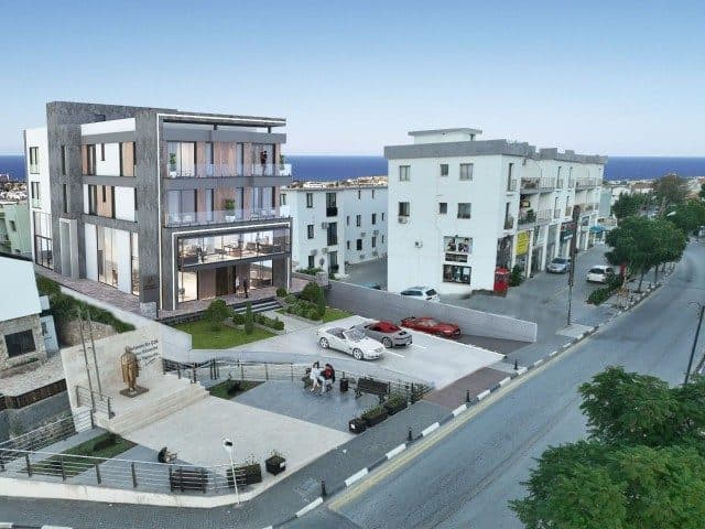 Balkonlu bina, yol kenarındaki otopark ve deniz arka planda