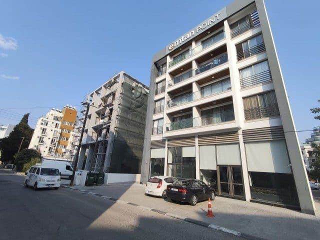 Cam balkonlu apartman cephesi ve önündeki park etmiş araçlar