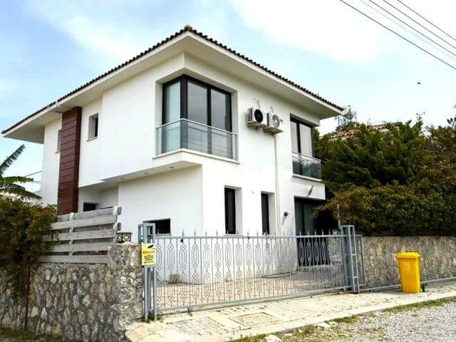 Beyaz cephe, cam balkonlar ve taş duvarlı çevre