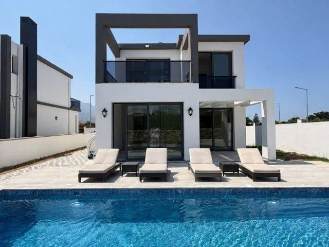 Havuz önünde şezlonglar, üst katta cam korkuluklu balkon
