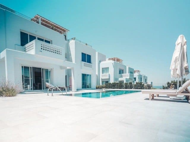 White apartments, a shared pool, and a broad paved area