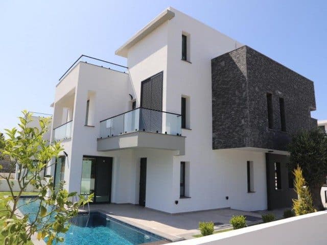 Beyaz ve koyu taş kaplamalı cephe, havuz ve cam korkuluklu balkon