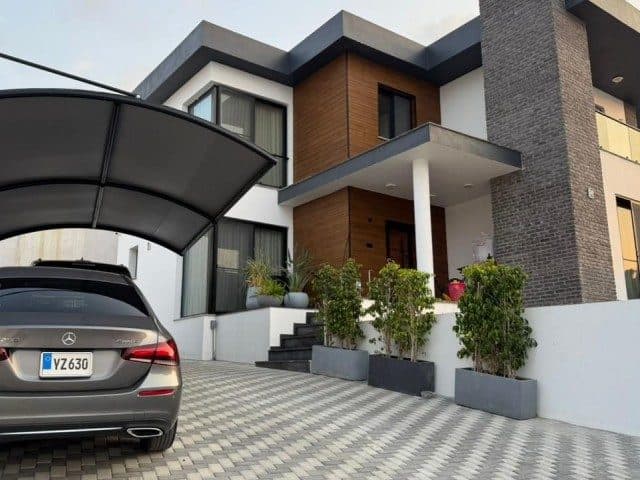 Ahşap kaplamalı giriş, saksı bitkileri ve araç örtüsü
