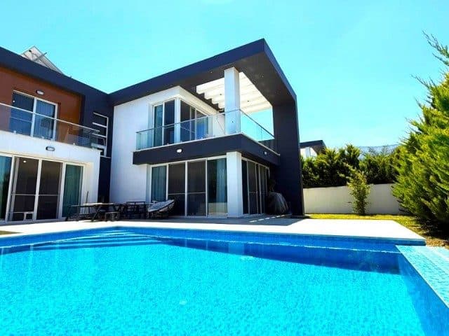 Cam balkonlu modern cephe, önünde mavi havuz ve oturma alanı