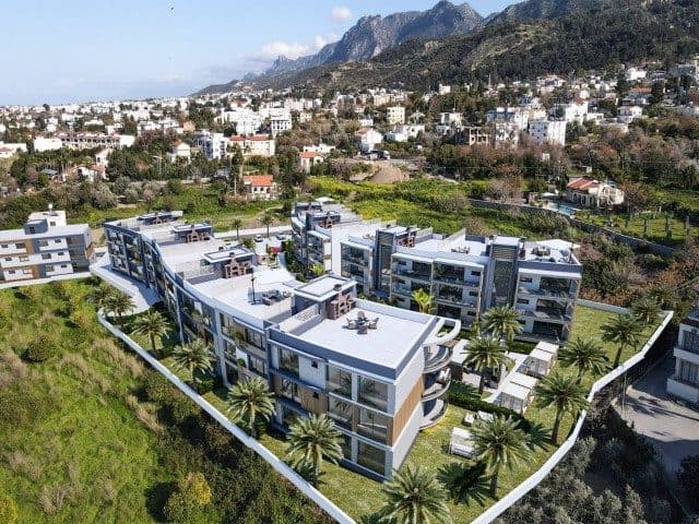 Modern bloklar palmiye ağaçları ve dağ yamaçları arasında görülüyor
