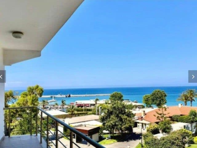 Balkon korkuluğunun ardından deniz ve kıyı görünüyor