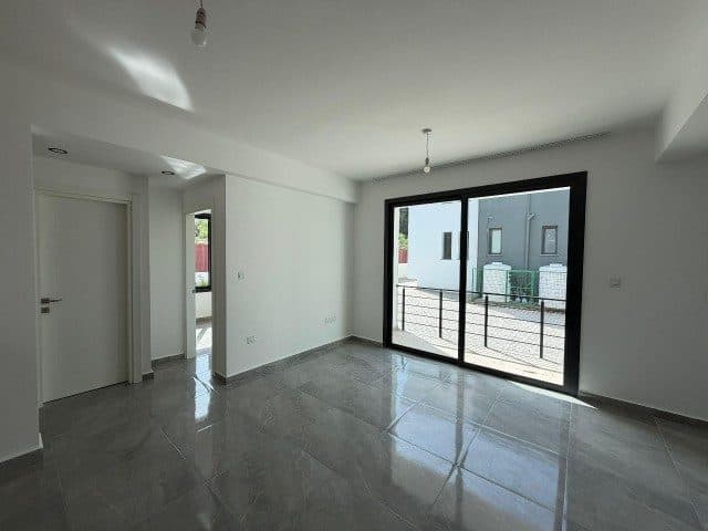 Gri fayanslı boş salon, geniş cam kapıyla balkona açılıyor