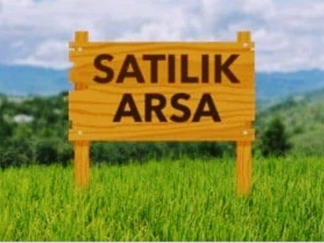 Yeşil arazide ahşap ilan tabelası, arkada tepeler