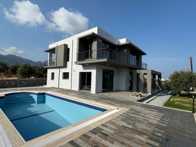 Havuz ve taş döşeli teras önünde beyaz, koyu detaylı villa