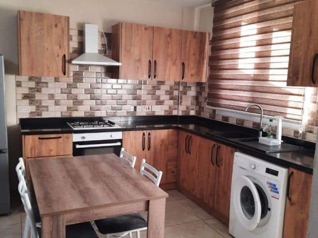 Kitchen with wooden cabinets, a table, oven and washing machine