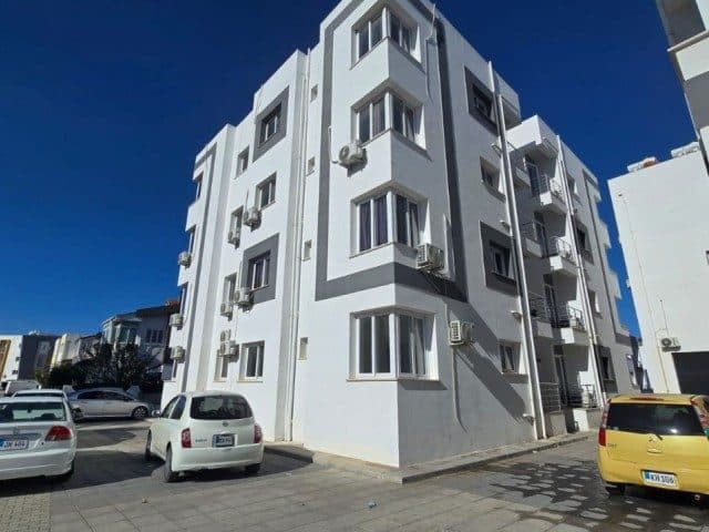 White and gray facade, corner windows, and parked cars
