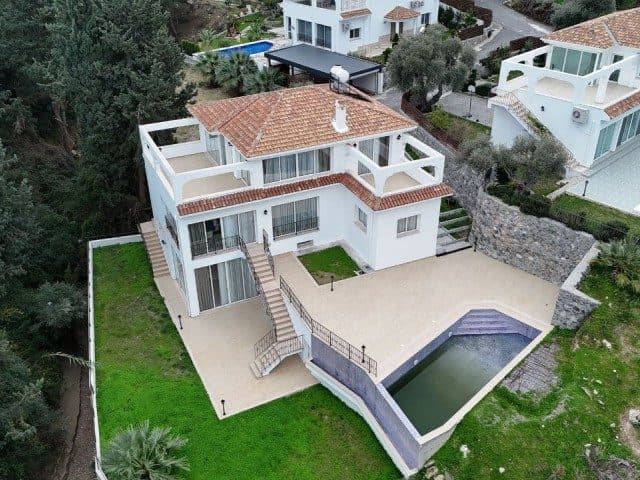 Kiremit çatılı beyaz villa, bahçe ve havuzla çevrili