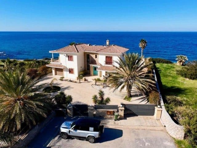 Kiremit çatılı villa, palmiye ağaçları ve denize bakıyor