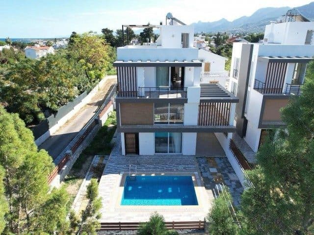 Villa and pool viewed from the front, with sea and mountains behind