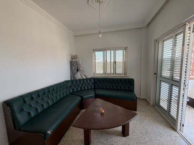 Koyu yeşil köşe koltuk ve açık balkon kapısı