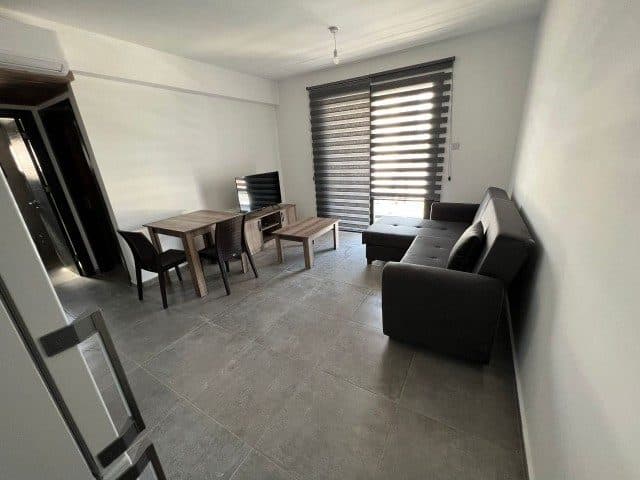 Salon, çizgili stor perdeler ve yemek masası yönünden görülüyor