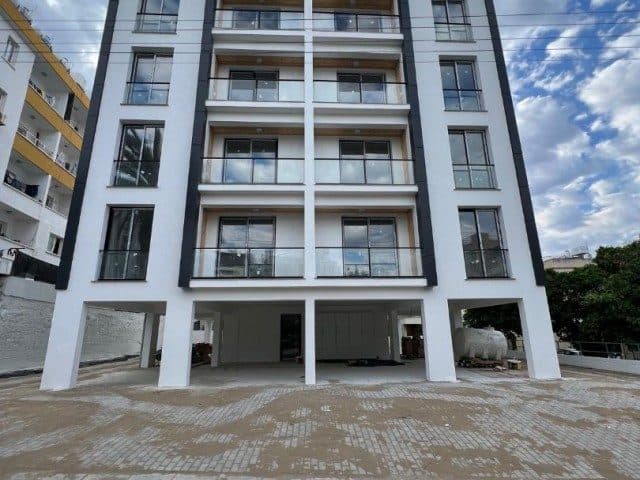 Apartment facade with balconies and open parking spaces at ground level