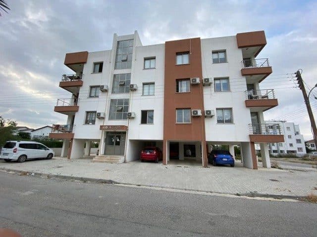 Beyaz ve kahverengi cephede balkonlar ve zemin kat park alanı