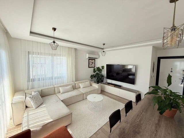 Living room with a cream corner sofa, wall-mounted TV and round table