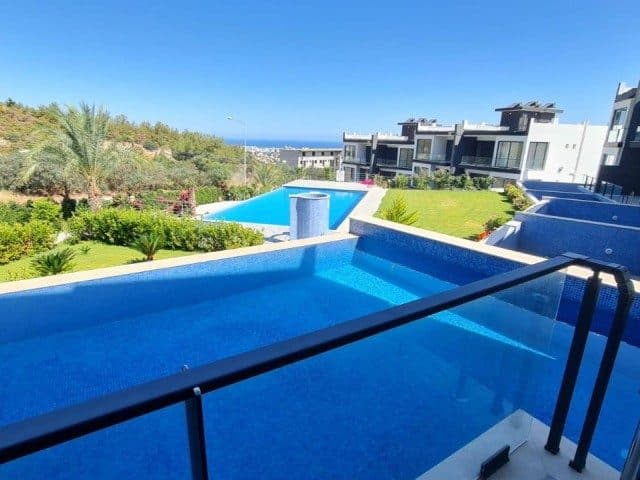 Balkon korkuluğunun önünde mavi havuzlar ve uzakta deniz
