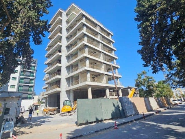 Çok katlı binanın balkonlu cephesi, çevresi inşaat bariyerleriyle çevrili