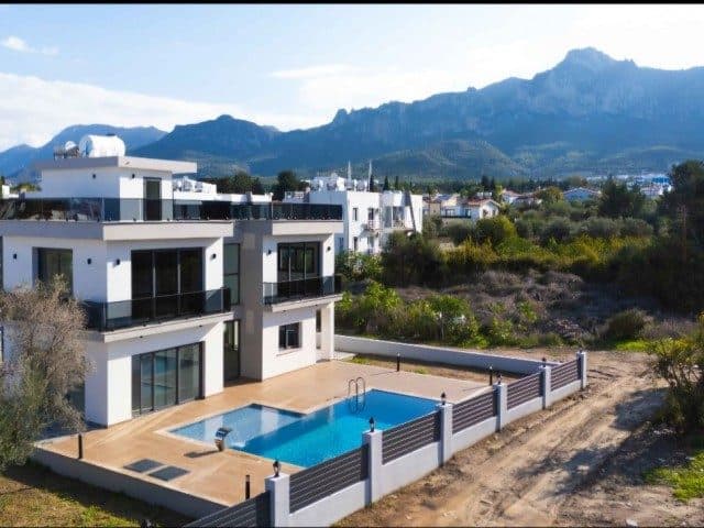 Beyaz cepheli villa, özel havuz ve dağ siluetiyle görünüyor