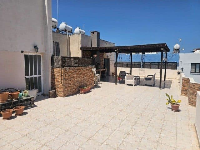 Geniş karo terasta pergola, oturma grubu ve saksılar görülüyor.