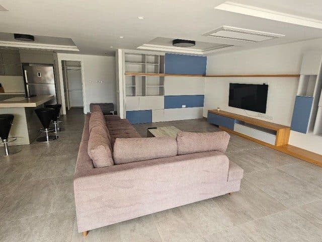 Pudra tonlu köşe koltuk ve mavi detaylı TV ünitesi
