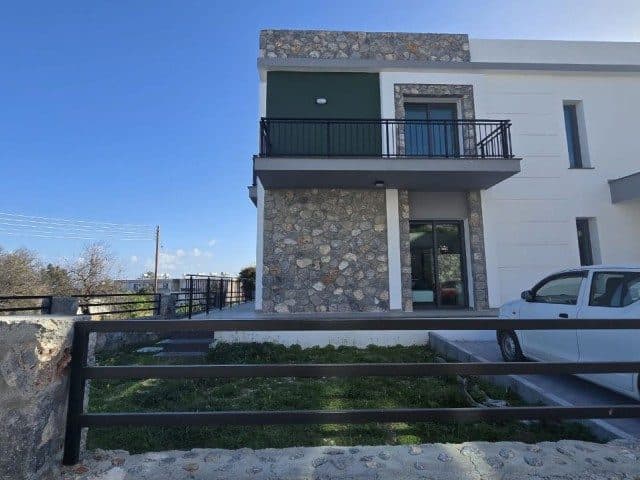 Taş kaplamalı cephe, üst balkon ve önünde park edilmiş araç