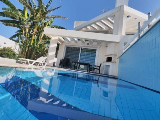 Havuz kenarında beyaz pergola, masa ve duvar tipi barbekü