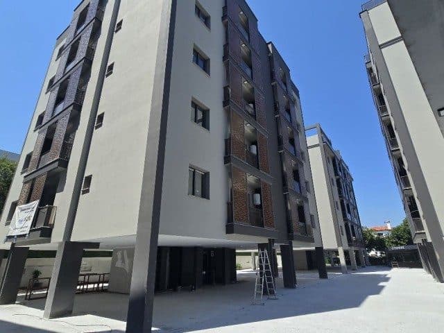 Açık renkli apartman cephesinde koyu balkon kaplamaları görülüyor