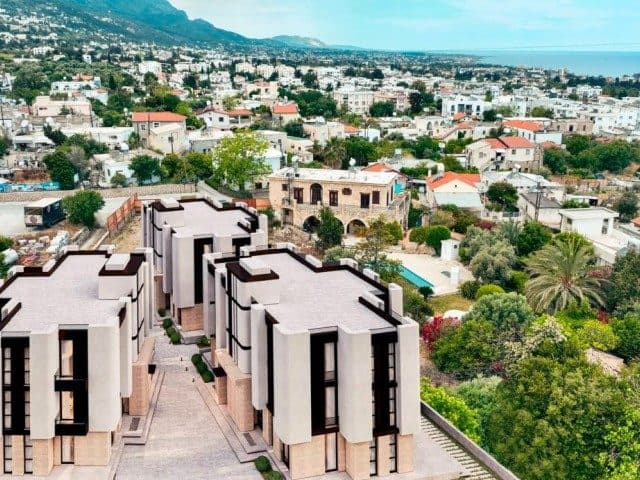 Modern façades in front, with the sea and mountains in the distance