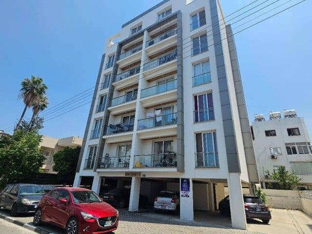 Açık renkli apartman cephesi ve zemin kattaki park alanı