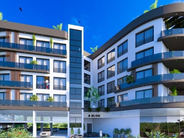 Balkonlu blokların ortasında camlı dikey cephe ve açık otopark