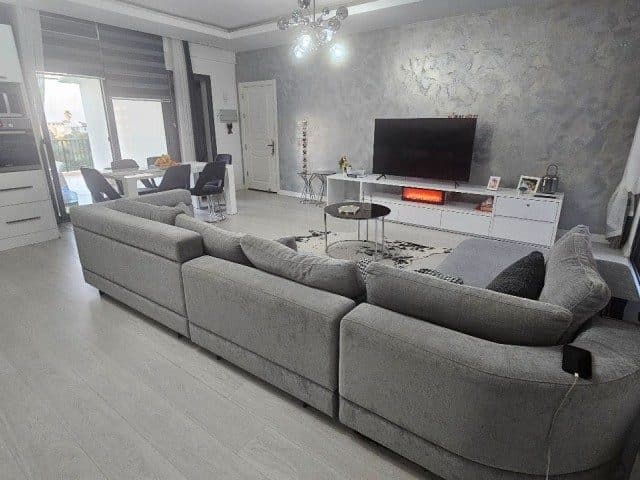Gri köşe koltuk, televizyon ve balkon kapısı