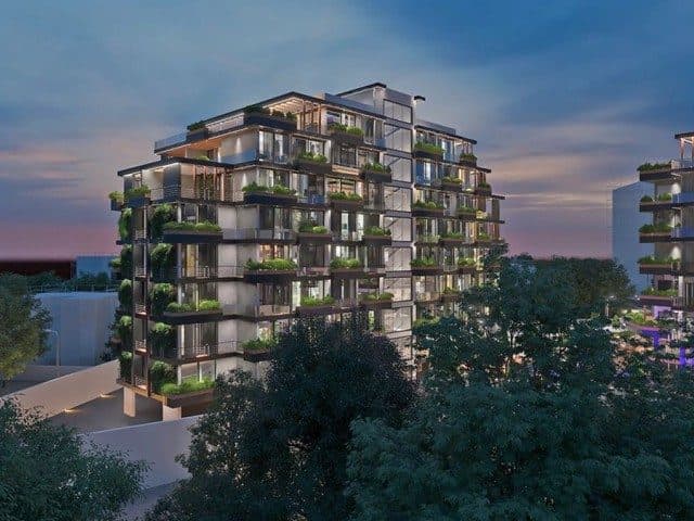 An apartment block with glass balconies rises among the trees
